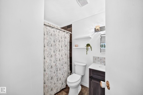 Bathroom featuring a built-in vanity with a white countertop, patterned tile backsplash, wall-mounted light fixture, and wood-finish flooring - 64 Habitat Crescent Nw, Edmonton, AB - Indoor Photo Showing Bathroom