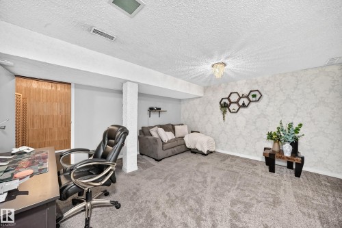 Carpeted room featuring a decorative wall, recessed lighting, and a prominent ceiling fixture - 64 Habitat Crescent Nw, Edmonton, AB - Indoor