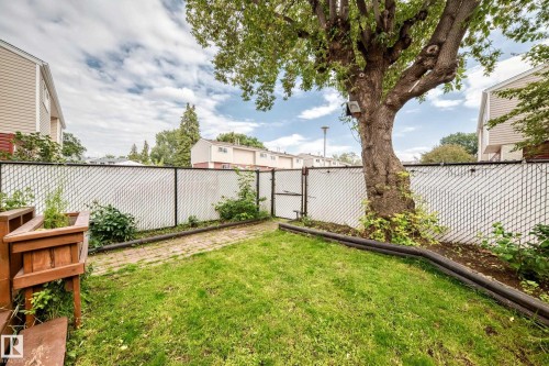 Fenced backyard featuring a mature tree, lawn area, and a brick pathway - 64 Habitat Crescent Nw, Edmonton, AB - Outdoor