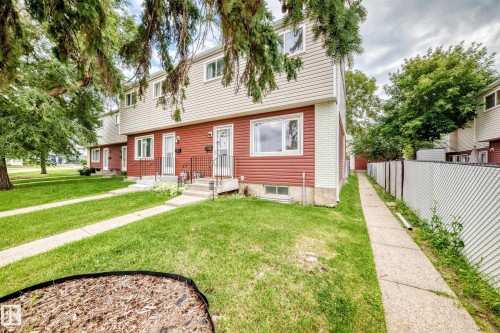Two-story townhouse featuring red and beige siding, white window frames, and a front lawn with a concrete walkway - 64 Habitat Crescent Nw, Edmonton, AB - Outdoor