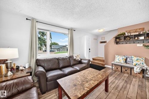 Wood-finish flooring throughout, large window, and built-in entry bench with storage - 64 Habitat Crescent Nw, Edmonton, AB - Indoor Photo Showing Living Room