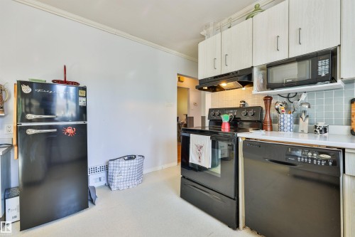 Kitchen featuring white upper cabinetry, light blue square tile backsplash, white countertops, a black range, and a black dishwasher and fridge. - 3824 111B Street Nw, Edmonton, AB - Indoor Photo Showing Kitchen