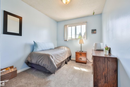 Second bedroom on main level. Light blue wall finish with textured ceiling, two open doorways, and gray carpet flooring - 3824 111B Street Nw, Edmonton, AB - Indoor Photo Showing Bedroom