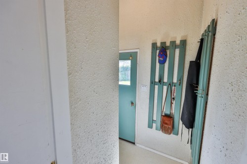 Back door entryway with textured walls, a teal-painted door, and built-in coat rack - 3824 111B Street Nw, Edmonton, AB -  Photo Showing Other Room