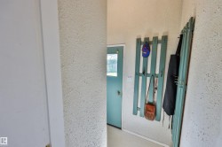 Back door entryway with textured walls, a teal-painted door, and built-in coat rack - 