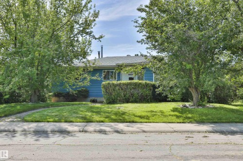 Blue exterior wood siding with white trim, mature trees, and a concrete pathway. East-facing house - 3824 111B Street Nw, Edmonton, AB - Outdoor