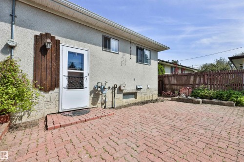 Exterior featuring a white entry door with security screen, concrete stucco siding, and a red brick paver patio - 3824 111B Street Nw, Edmonton, AB - Outdoor With Exterior