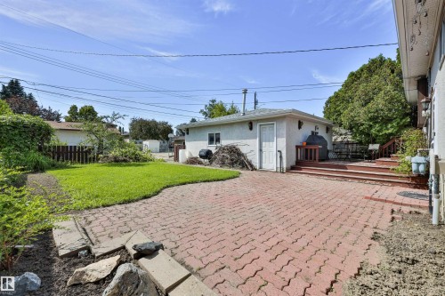 Spacious west-facing backyard, featuring a large brick paver patio, a wood deck, and a detached two-car garage. There are also grapevines, rhubarb, and many spots for a garden. - 3824 111B Street Nw, Edmonton, AB - Outdoor