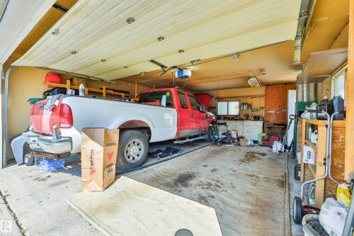 Spacious garage featuring a concrete floor, overhead garage door, built-in shelving, and a workbench with cabinets - 3824 111B Street Nw, Edmonton, AB - Indoor Photo Showing Garage