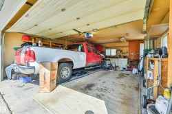 Spacious garage featuring a concrete floor, overhead garage door, built-in shelving, and a workbench with cabinets - 