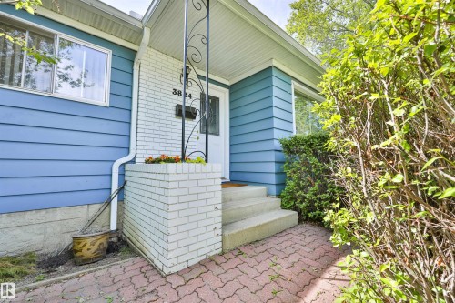 Front entrance featuring a concrete porch, white brick accents, and a wrought iron support column - 3824 111B Street Nw, Edmonton, AB - Outdoor