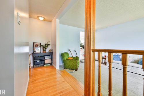 Hardwood flooring extending from the entryway, featuring a light wood railing and balusters - 3824 111B Street Nw, Edmonton, AB - Indoor Photo Showing Other Room
