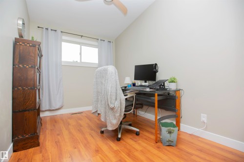 Bright home office featuring hardwood flooring, large window with natural light, and a dedicated work desk with ergonomic seating - 9107 58 Street Nw, Edmonton, AB - Indoor Photo Showing Office