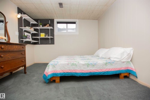Carpeted flooring, white paneled wall, built-in wall shelving, and a window with blinds - 9107 58 Street Nw, Edmonton, AB - Indoor Photo Showing Bedroom