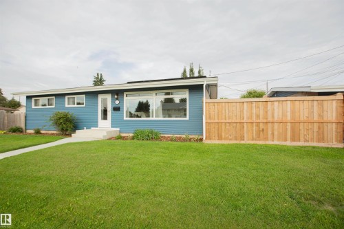 Modern blue siding exterior with large picture windows, concrete front walkway, and manicured lawn - 9107 58 Street Nw, Edmonton, AB - Outdoor