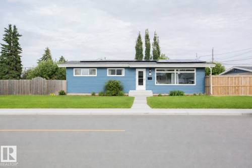 Modern blue ranch-style home featuring a clean horizontal facade with multi-pane windows, a covered carport entry, and manicured landscaping - 9107 58 Street Nw, Edmonton, AB - Outdoor With Facade