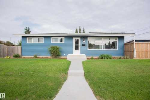 Modern ranch-style home featuring a fresh blue exterior with horizontal siding, expansive front-facing windows, and a welcoming entry with glass door - 9107 58 Street Nw, Edmonton, AB - Outdoor