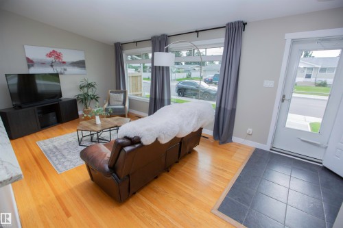 Spacious primary suite showcasing wood-finish flooring, and abundant natural light from multiple windows - 9107 58 Street Nw, Edmonton, AB - Indoor Photo Showing Living Room