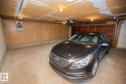 Spacious attached garage featuring epoxy-coated concrete flooring, recessed LED ceiling lighting, and ample storage capacity - 9107 58 Street Nw, Edmonton, AB - Indoor Photo Showing Garage
