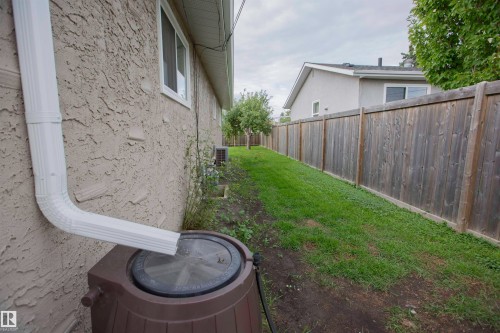 Spacious side yard with mature landscaping, manicured lawn, and established wooden privacy fencing - 9107 58 Street Nw, Edmonton, AB - Outdoor