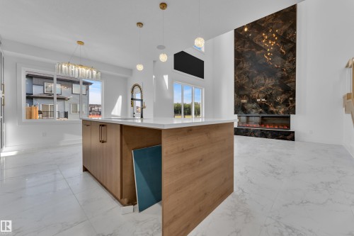 Kitchen island with wood-finish cabinetry, white countertop, and gold-finish hardware - 2039 156 Avenue Nw, Edmonton, AB - Indoor Photo Showing Kitchen
