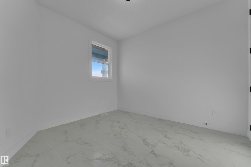 White walls with a single window, featuring light-colored flooring with a subtle veined pattern - 2039 156 Avenue Nw, Edmonton, AB - Indoor Photo Showing Other Room
