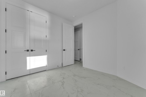 White panel doors with black hardware, white walls, and light-toned, veined tile flooring - 2039 156 Avenue Nw, Edmonton, AB - Indoor Photo Showing Other Room