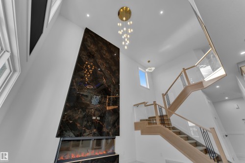 Two-story interior with a dark-toned accent wall featuring an integrated linear fireplace - 2039 156 Avenue Nw, Edmonton, AB - Indoor Photo Showing Other Room
