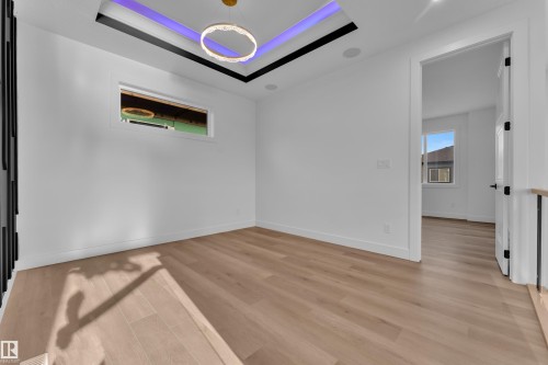 Recessed ceiling with perimeter lighting and a central ring chandelier - 2039 156 Avenue Nw, Edmonton, AB - Indoor Photo Showing Other Room