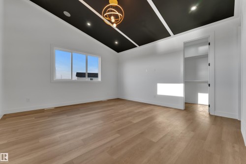 Wood-finish flooring, accent ceiling treatment, a multi-pane window, and an open closet - 2039 156 Avenue Nw, Edmonton, AB - Indoor Photo Showing Other Room