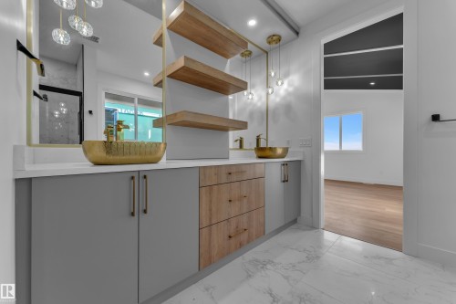Dual gold vessel sinks with gold-tone fixtures, suspended lighting, and a floating vanity featuring wood-finish and gray cabinetry - 2039 156 Avenue Nw, Edmonton, AB - Indoor