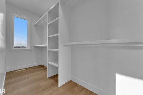 Built-in shelving, hanging rods, light wood-finish flooring, and a window with trim - 2039 156 Avenue Nw, Edmonton, AB - Indoor With Storage