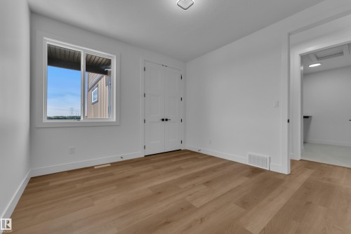 Wood-finish flooring, white walls, double panel doors, and a window with white trim - 2039 156 Avenue Nw, Edmonton, AB - Indoor Photo Showing Other Room