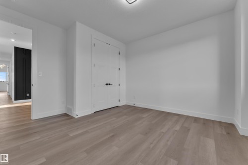 Light wood-finish flooring, white walls, and a flush-mounted ceiling light fixture - 2039 156 Avenue Nw, Edmonton, AB - Indoor Photo Showing Other Room