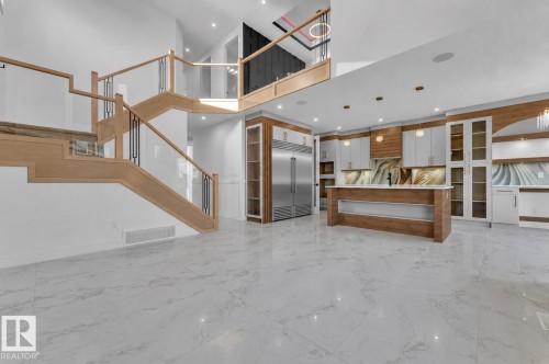 White marble-look flooring throughout, two-story open-concept design, wood-finish and glass staircase, kitchen island with integrated lighting, and integrated stainless steel refrigerator - 2039 156 Avenue Nw, Edmonton, AB - Indoor Photo Showing Other Room