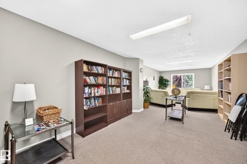 Carpeted common area featuring built-in shelving, recessed lighting, and large window - #324 279 Suder Greens Dr Nw, Edmonton, AB - Indoor