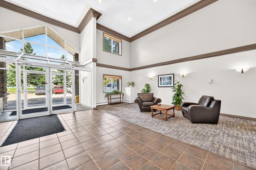 Vaulted ceiling entry featuring glass double doors, large transom windows, and a tiled floor - #324 279 Suder Greens Dr Nw, Edmonton, AB - Indoor