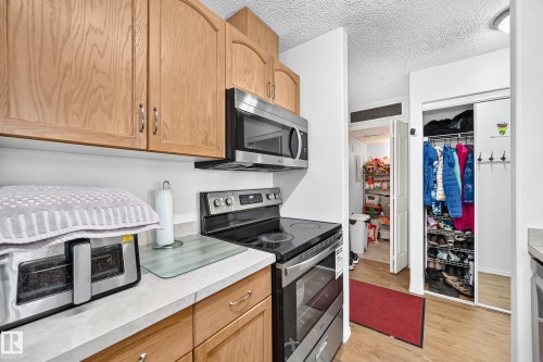 Kitchen featuring wood cabinetry, stainless steel microwave, and stainless steel electric range - #324 279 Suder Greens Dr Nw, Edmonton, AB - Indoor Photo Showing Kitchen