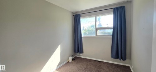 Neutral gray walls with white trim, brown carpet flooring, and a large window - 4317 50 Street, Vegreville, AB - Indoor