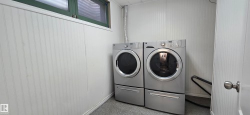 White beadboard wall paneling, window with dark green trim, light gray carpeting, and a white door with a polished chrome knob - 4317 50 Street, Vegreville, AB - Indoor Photo Showing Laundry Room