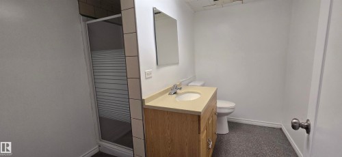 Shower enclosure with a sliding door, vanity with an integrated sink, and a wall-mounted mirror - 4317 50 Street, Vegreville, AB - Indoor Photo Showing Bathroom