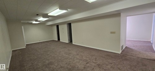 Expansive carpeted room with multiple recessed light fixtures and a drop ceiling - 4317 50 Street, Vegreville, AB - Indoor
