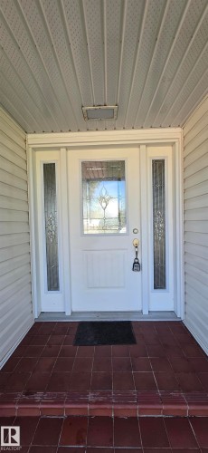 Entryway featuring a white door with decorative glass, two sidelight windows, a tiled porch, and a stepped entry - 4317 50 Street, Vegreville, AB - Outdoor With Exterior