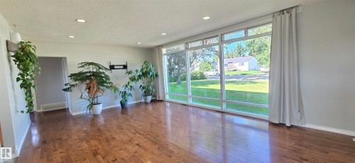Expansive windows featuring a streetscape, recessed ceiling lights, and wood-finish flooring - 4317 50 Street, Vegreville, AB - Indoor Photo Showing Other Room