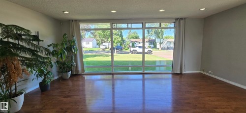 Expansive window wall, recessed ceiling lighting, wood-finish flooring, and light gray wall paint - 4317 50 Street, Vegreville, AB - Indoor Photo Showing Other Room