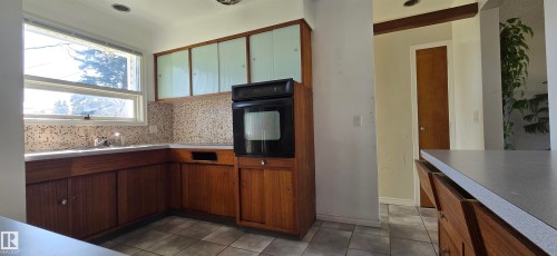 Kitchen featuring wood-finish cabinetry, a built-in oven, and a mosaic tile backsplash - 4317 50 Street, Vegreville, AB - Indoor