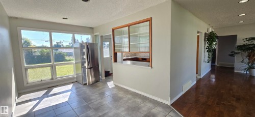Bright, open kitchen and dining area featuring sliding glass doors with natural light, stainless steel appliances, wood-finish flooring, and seamless access to outdoor spaces - 4317 50 Street, Vegreville, AB - Indoor Photo Showing Other Room