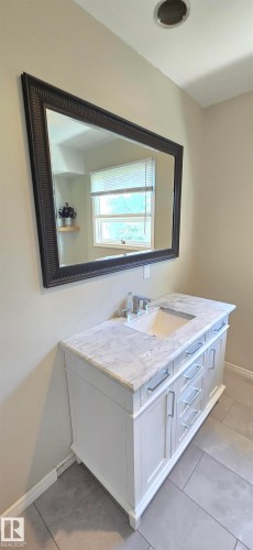 White vanity with a stone countertop and an undermount sink - 4317 50 Street, Vegreville, AB - Indoor Photo Showing Bathroom