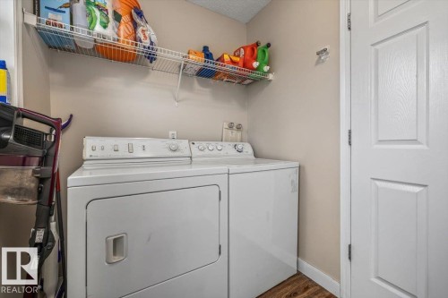 Dedicated laundry area with durable flooring, open wire shelving, and a paneled interior door - 4744 Terwillegar Common Nw, Edmonton, AB - Indoor Photo Showing Laundry Room