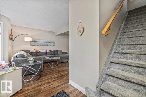 Wood-finish flooring, staircase with carpeted treads, light-toned wall paint, and white trim - 4744 Terwillegar Common Nw, Edmonton, AB - Indoor Photo Showing Other Room